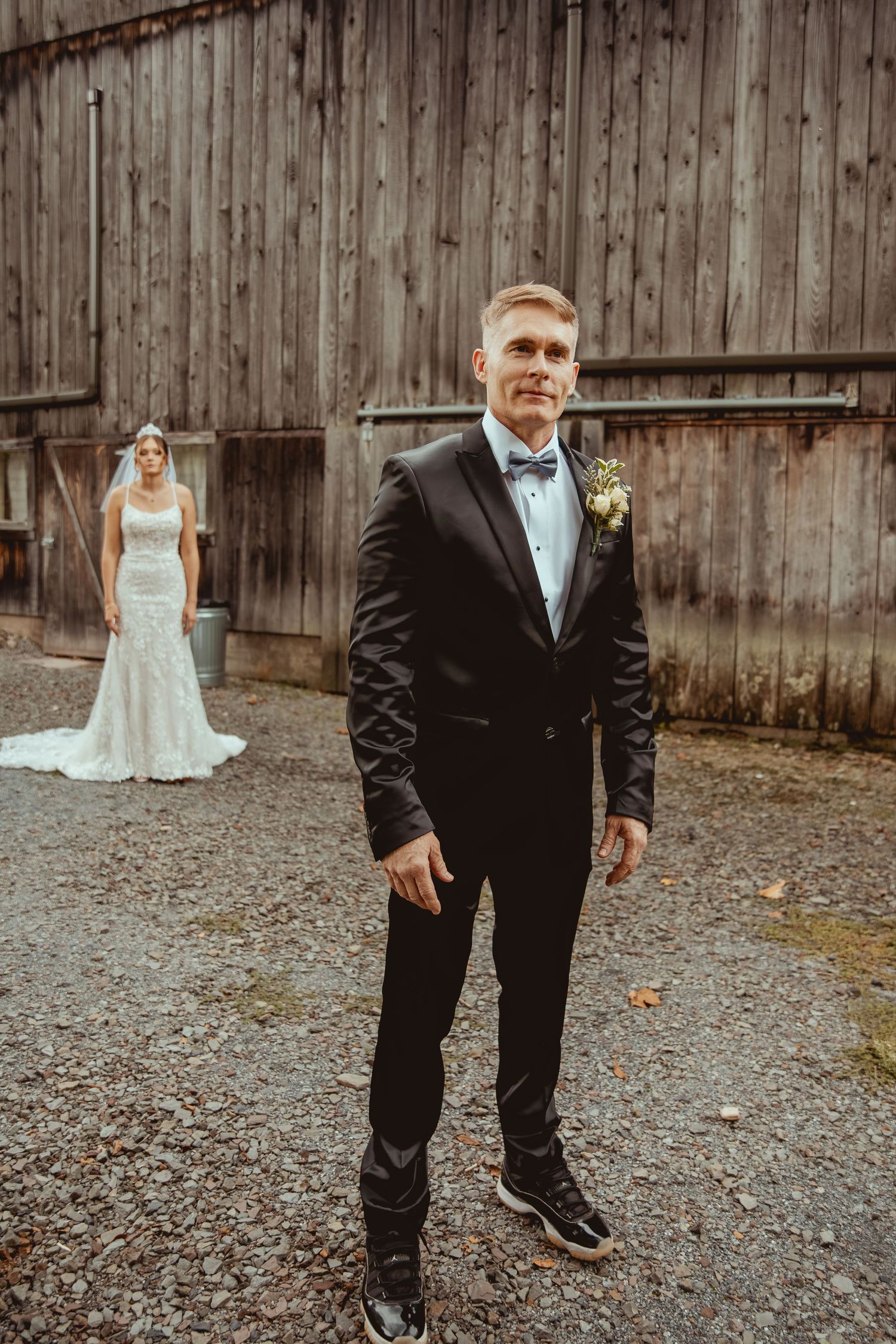 Wedding photo sequence showing a rustic wooden barn backdrop with formal attire and gravel ground.