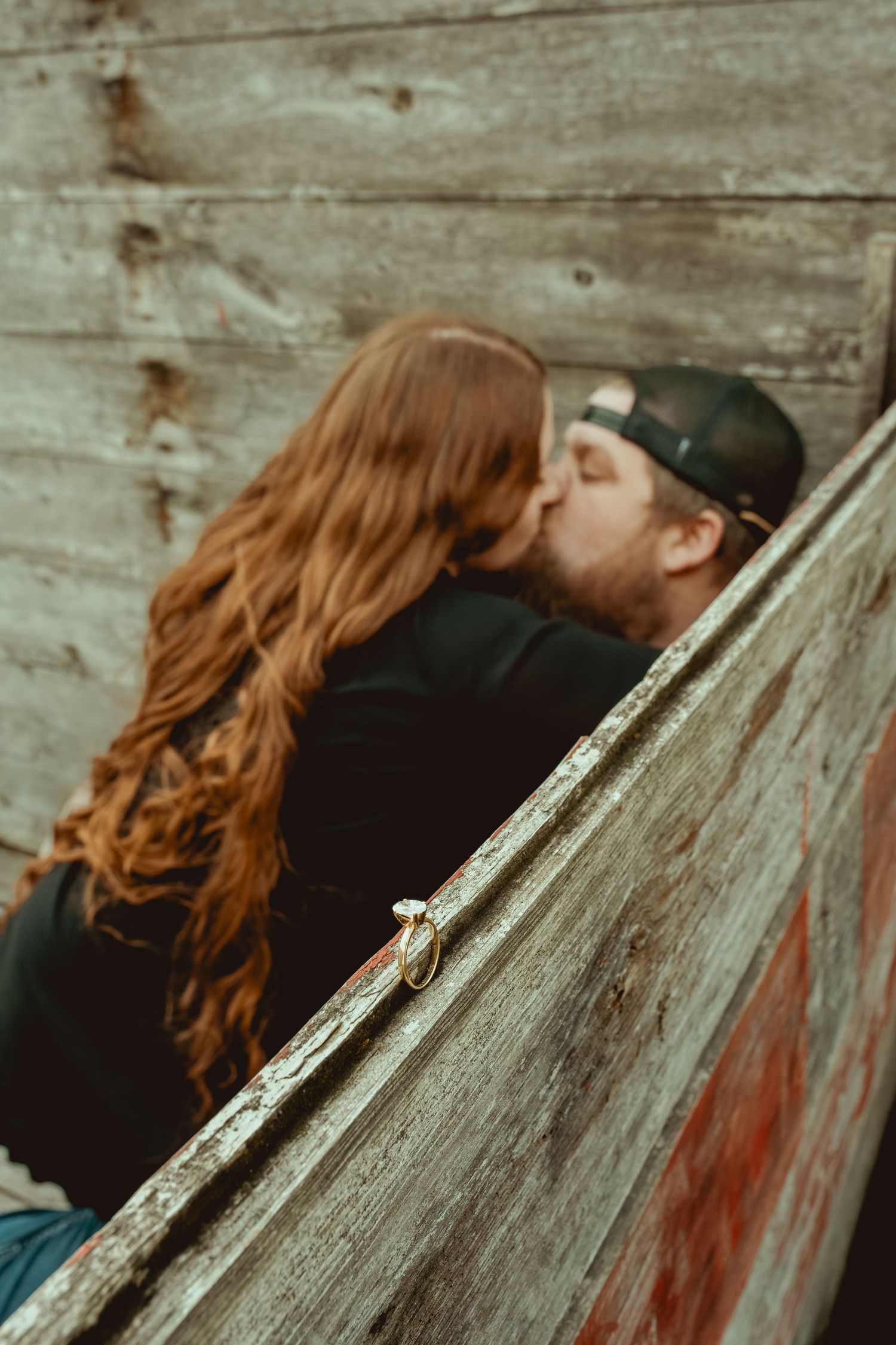 A person with red hair rests their head against a rustic wooden surface in a series of similar artistic shots.