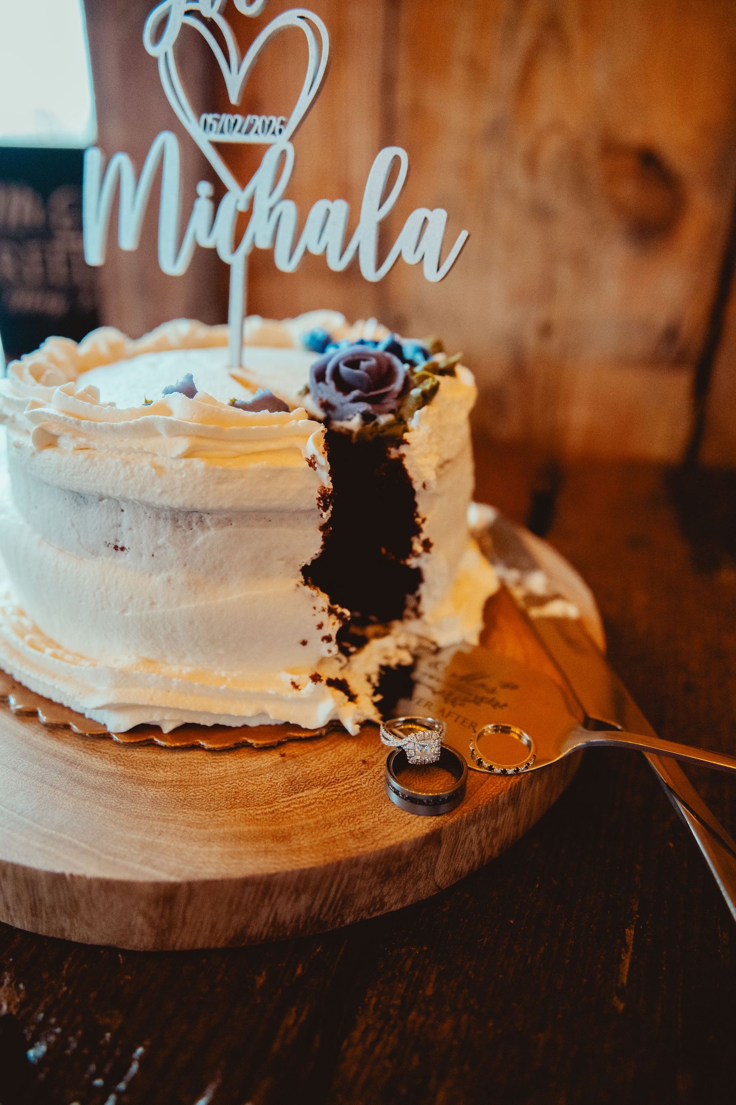 Single tier chocolate wedding cake with white frosting and Michala cake topper with wedding rings.