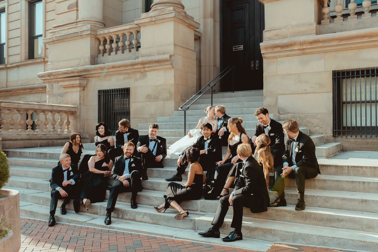 Wedding group photo session on ornate stone steps of a historic building.