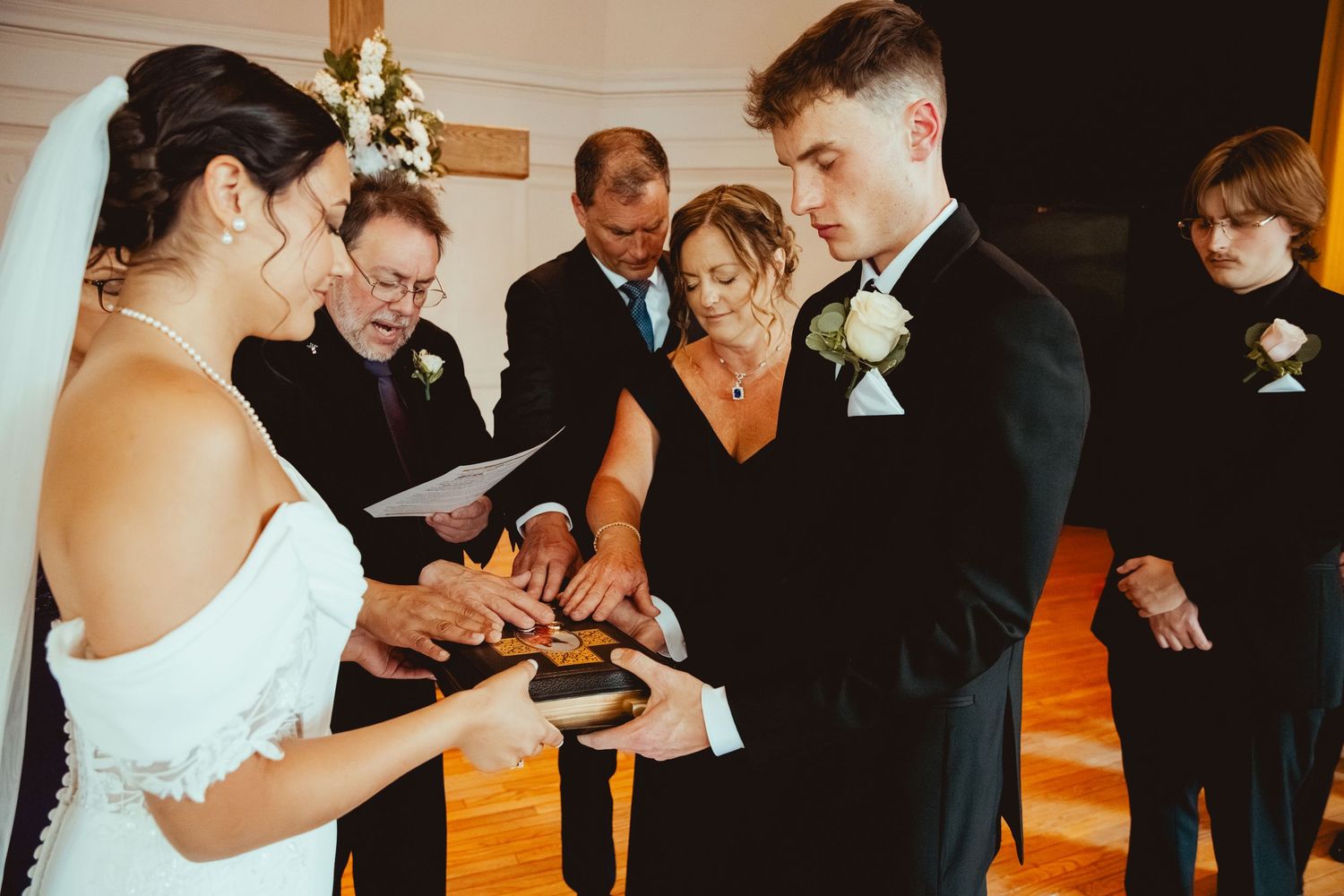 Wedding party poses together in a dark indoor venue with warm lighting and wooden floors.