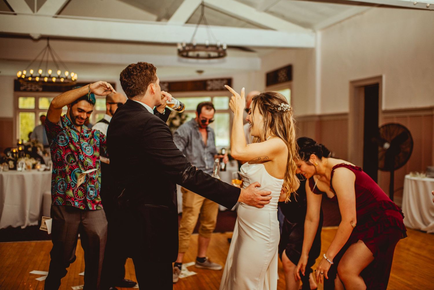 Guests dancing and celebrating at an evening wedding reception in a spacious ballroom.