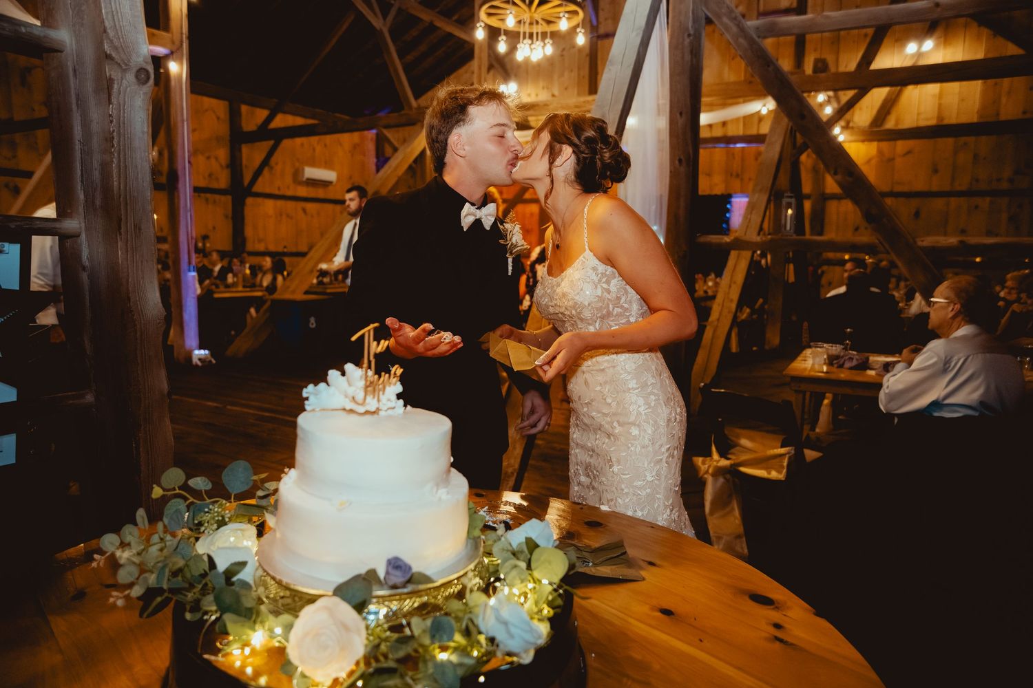 Romantic wedding reception scene with couples dancing and celebrating in a rustic barn venue with warm lighting.