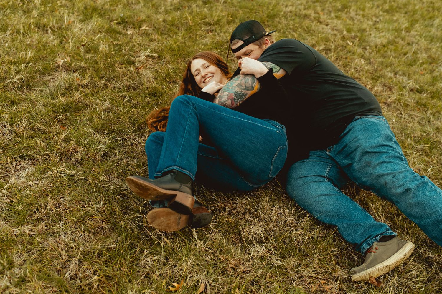 A sequence of seven photos showing someone rolling down a grassy hill in blue jeans and sneakers.