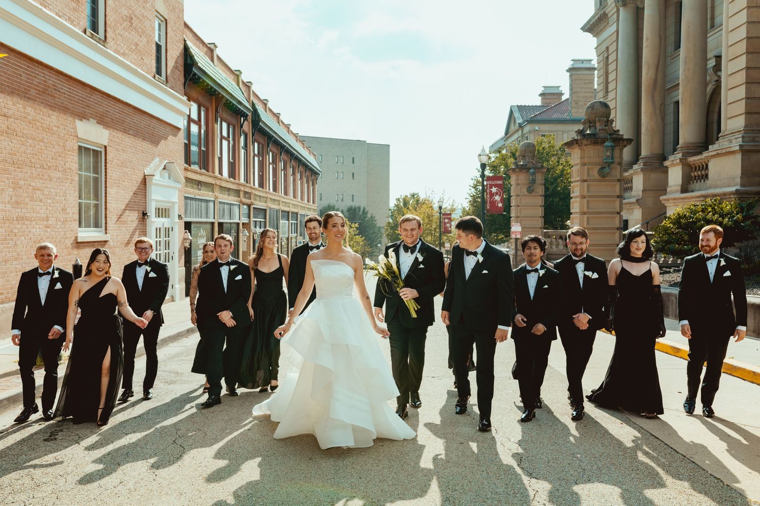 Wedding party walking in formation outside historic brick building with columns.