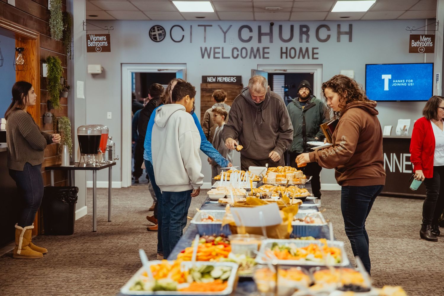 A church entrance with a 'Welcome Home' sign and tables set up for a gathering.