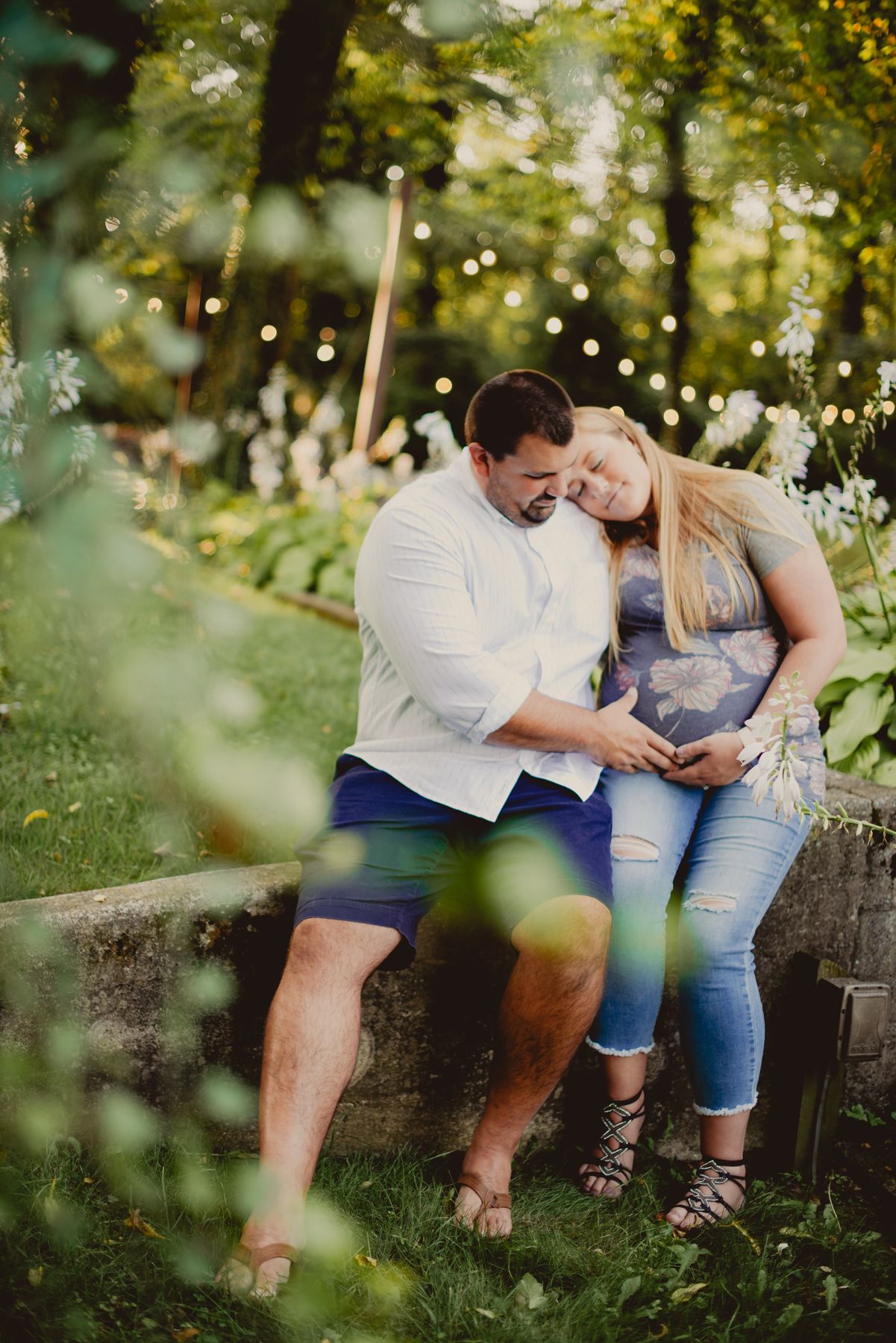 Couple sitting together on rustic wooden fence in sunlit garden with dreamy bokeh effect.