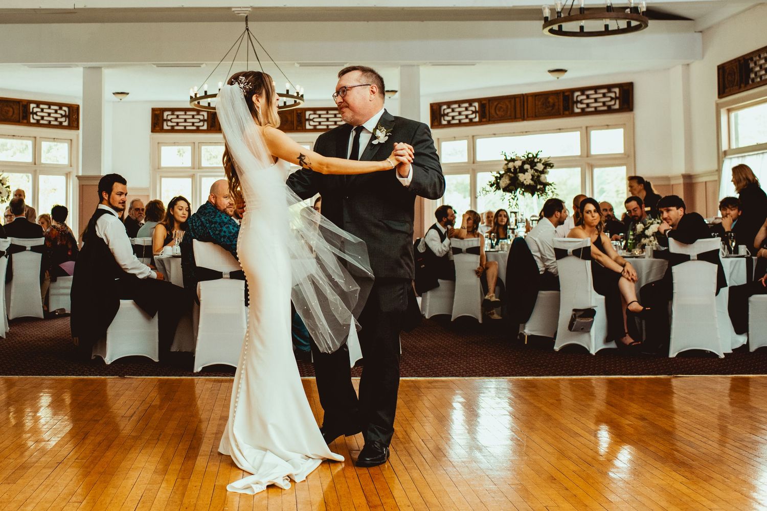 Wedding reception dance floor with guests celebrating in a rustic venue with wooden details.