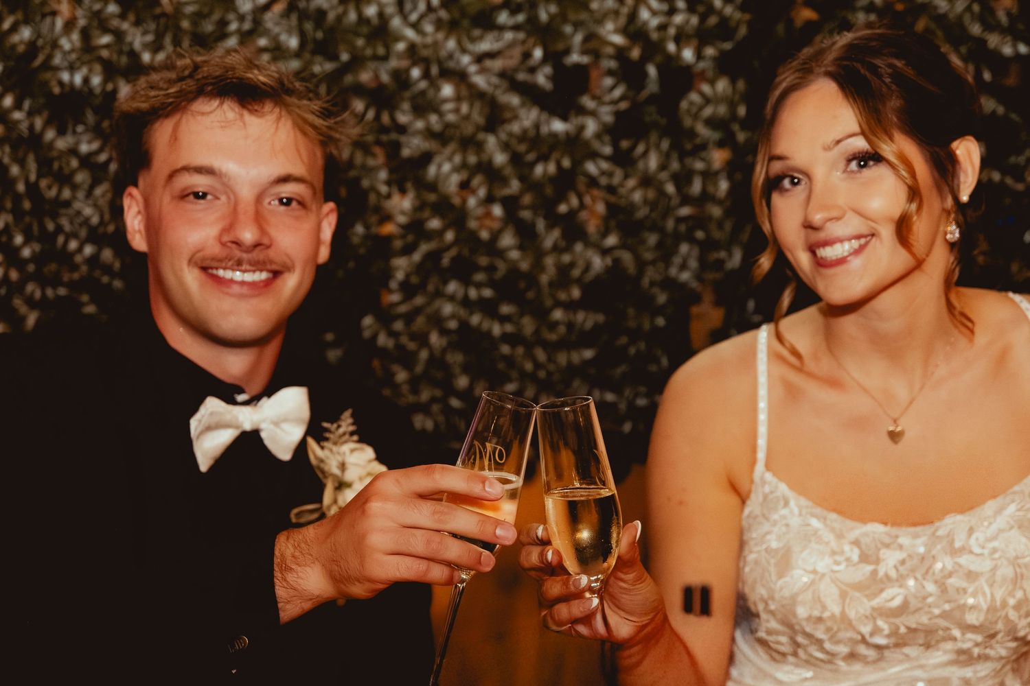 Wedding reception guests enjoying drinks and conversation in warm evening lighting.