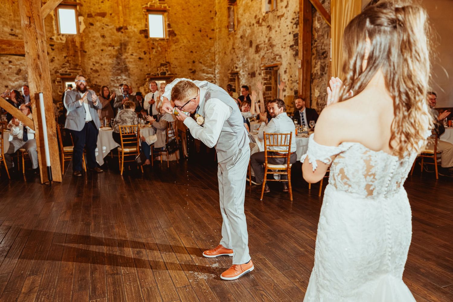 Wedding celebration in a rustic barn venue with warm lighting and wooden beams.