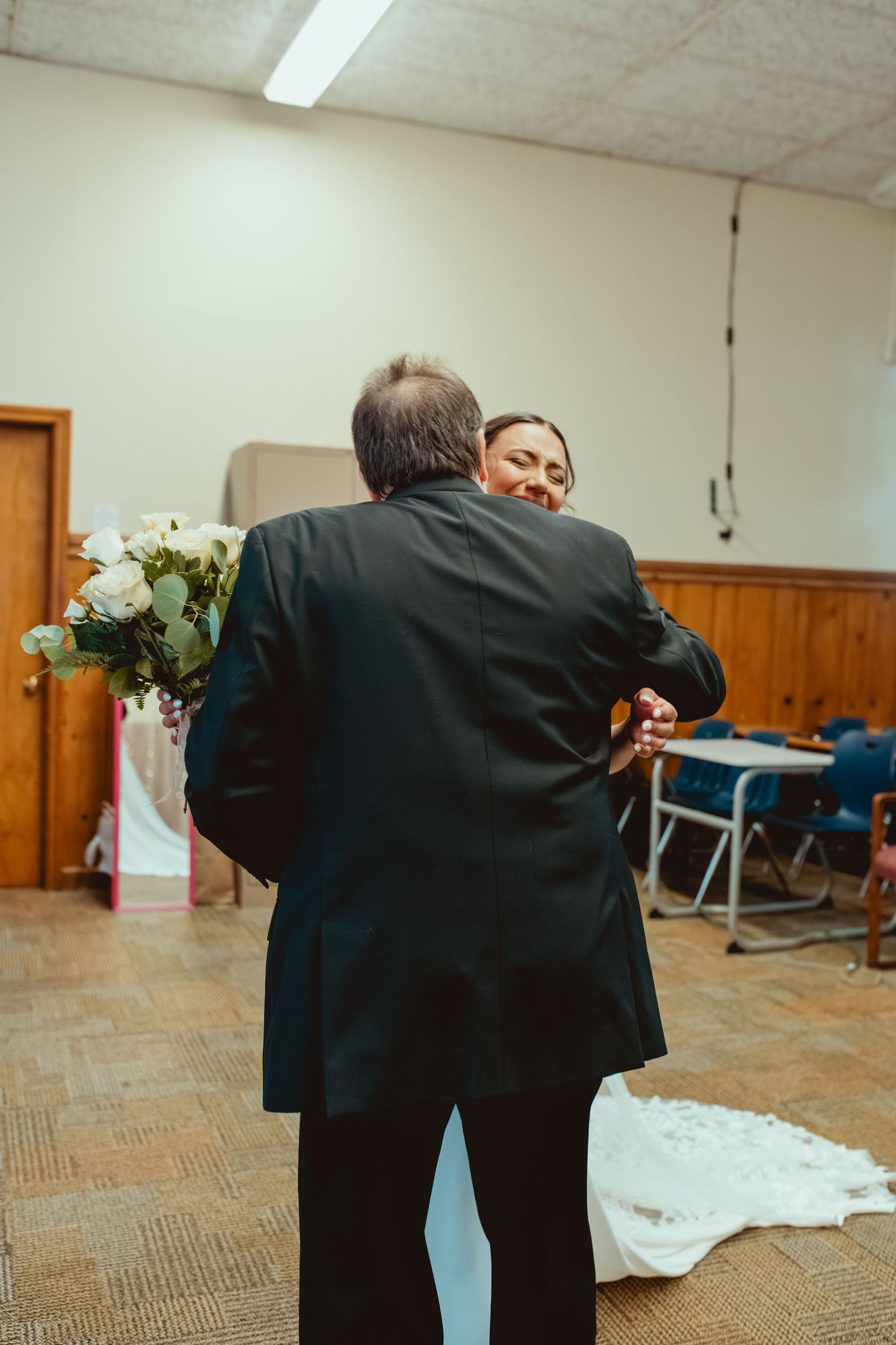 A couple shares an intimate dance moment in an indoor venue with carpeted floors and wooden accents.