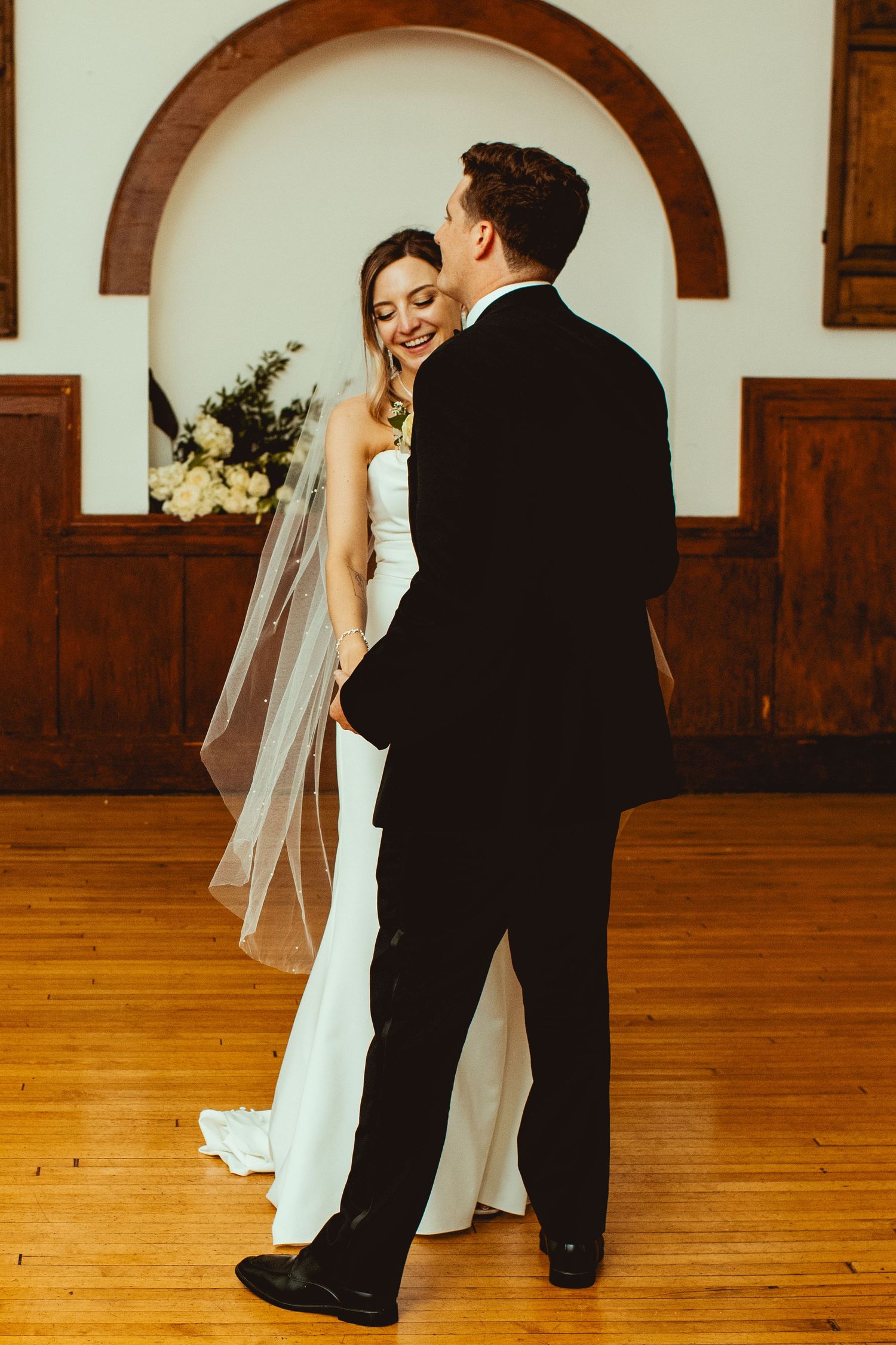Couple shares their first dance on a polished wooden dance floor in an elegant venue.