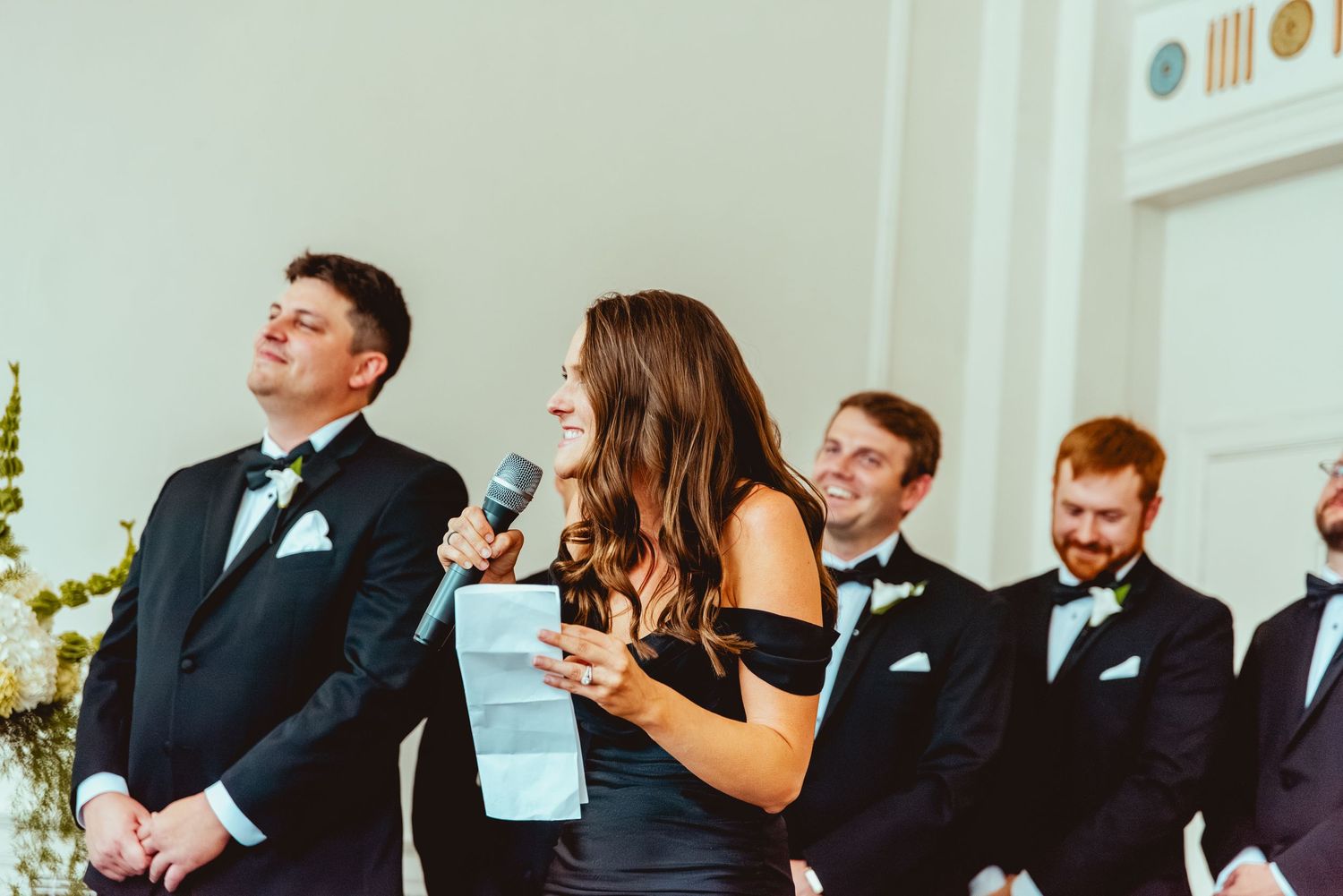 Wedding party laughing and celebrating during reception in an elegant white room.