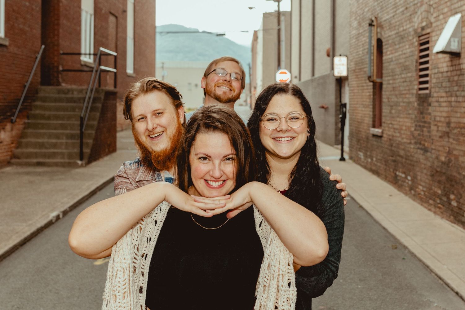 Friends gather for candid photos in an urban setting with brick architecture and natural lighting.