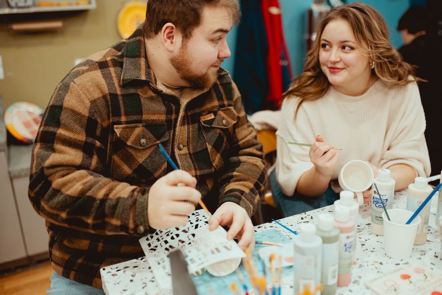 Couple sharing milkshakes and desserts at a cozy restaurant table with vintage decor.