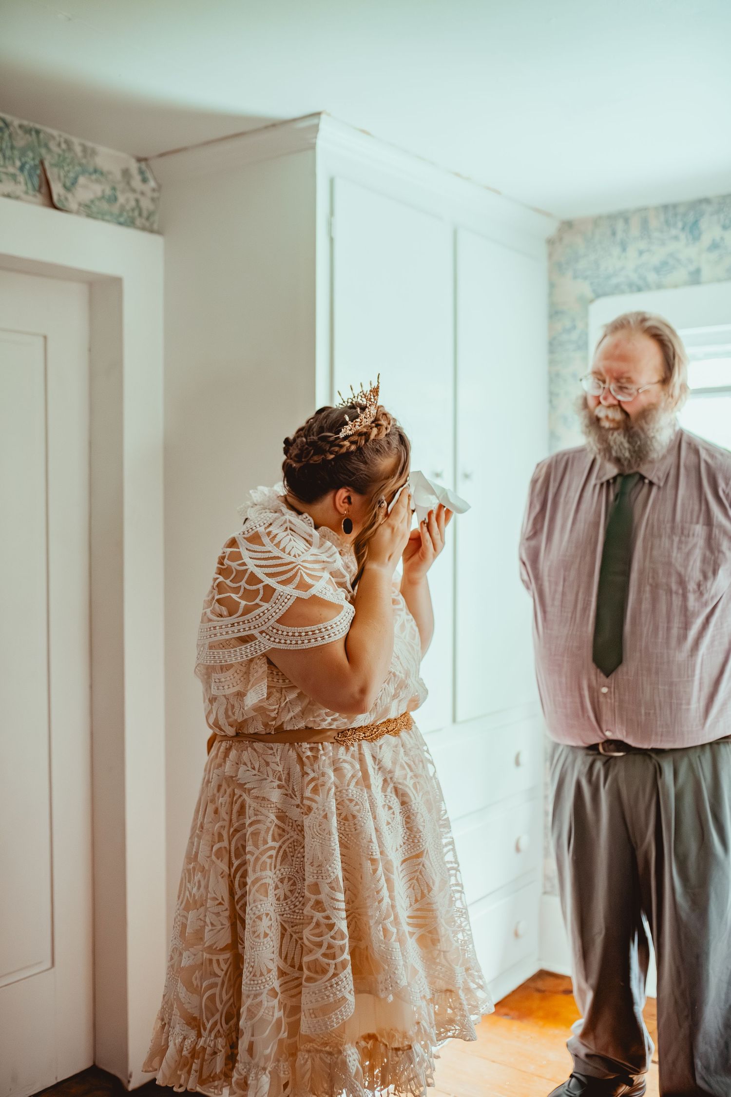 A series of emotional first look photos showing a bride in a lace dress meeting her father before the wedding ceremony.