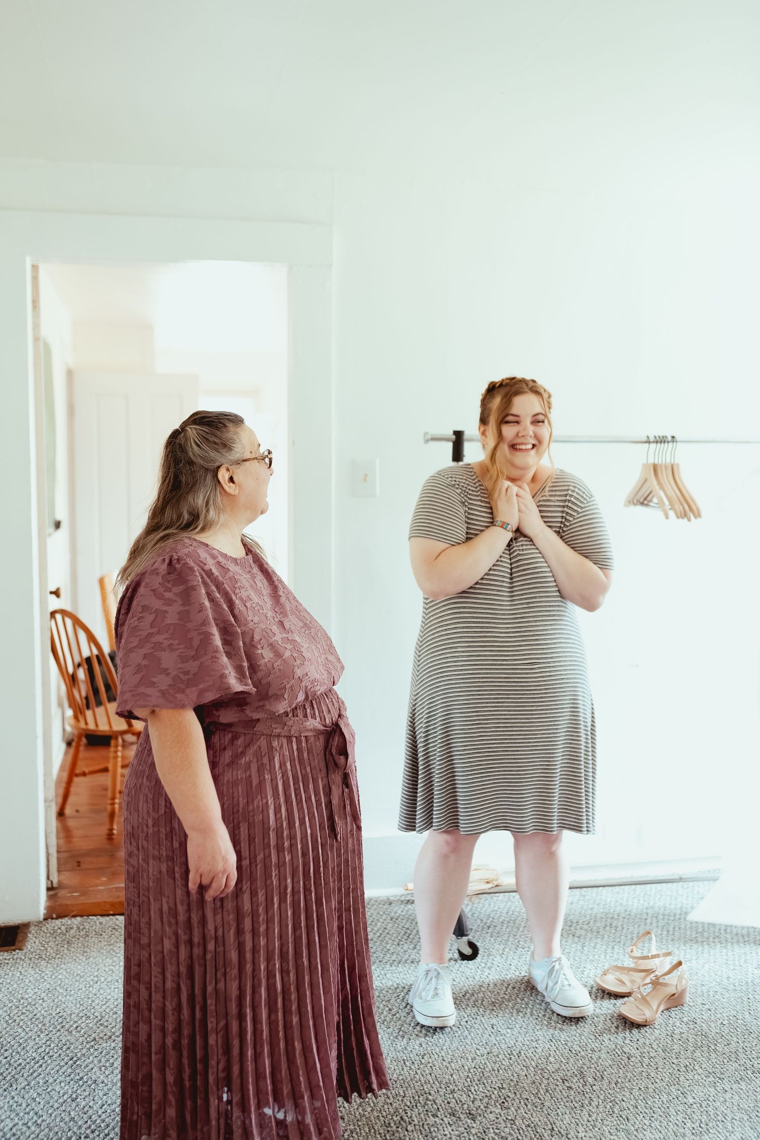 Two women in contrasting dresses share an emotional first look moment before a wedding.
