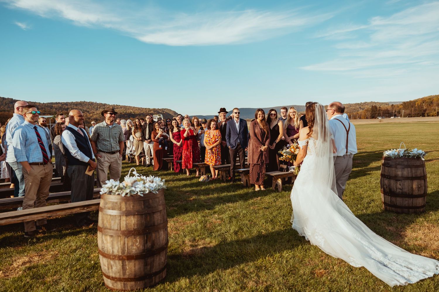 Scenic outdoor wedding venue with rustic wooden barrels and mountain views at golden hour.