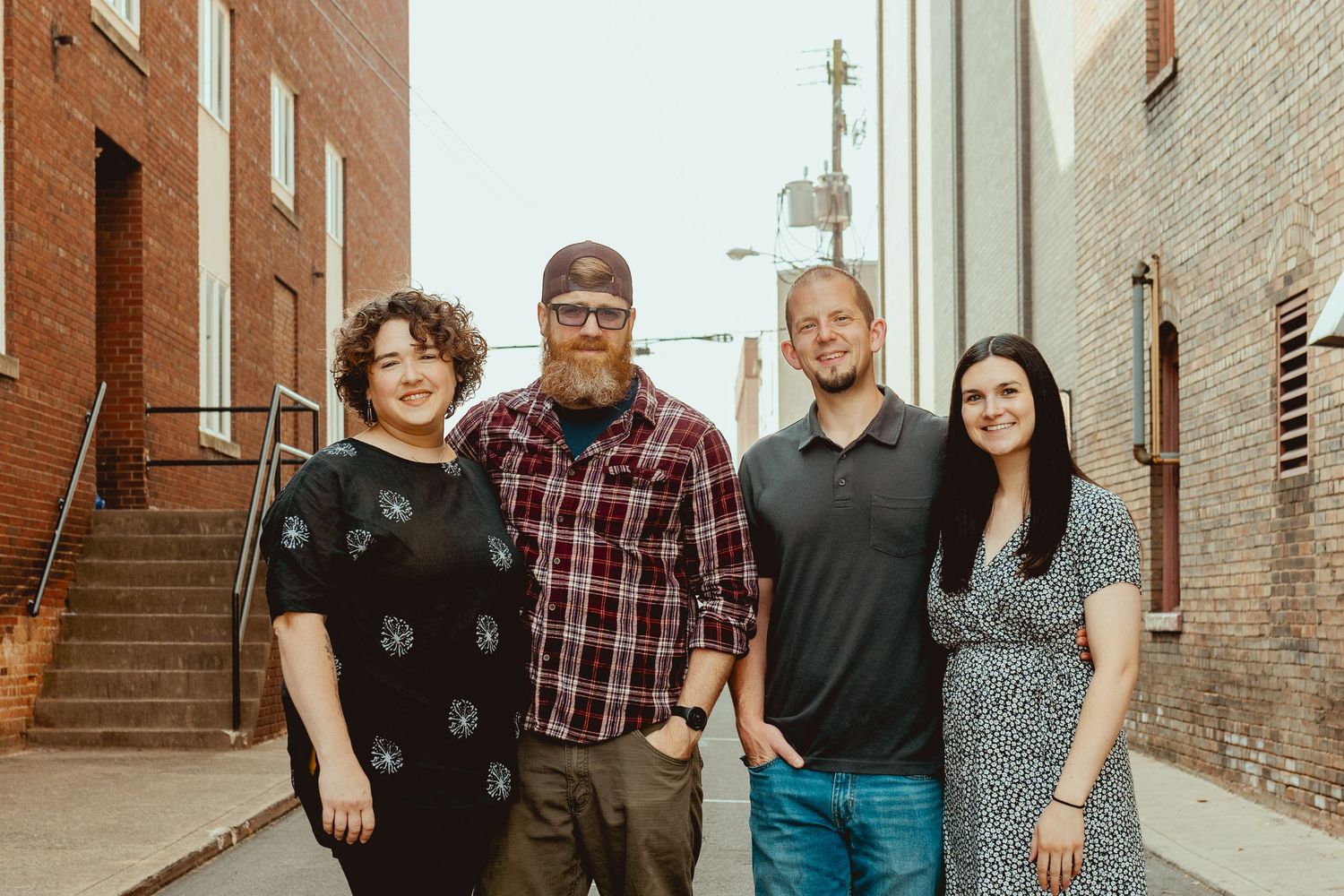 Family group posing together in an industrial urban setting with brick walls and metal fixtures.