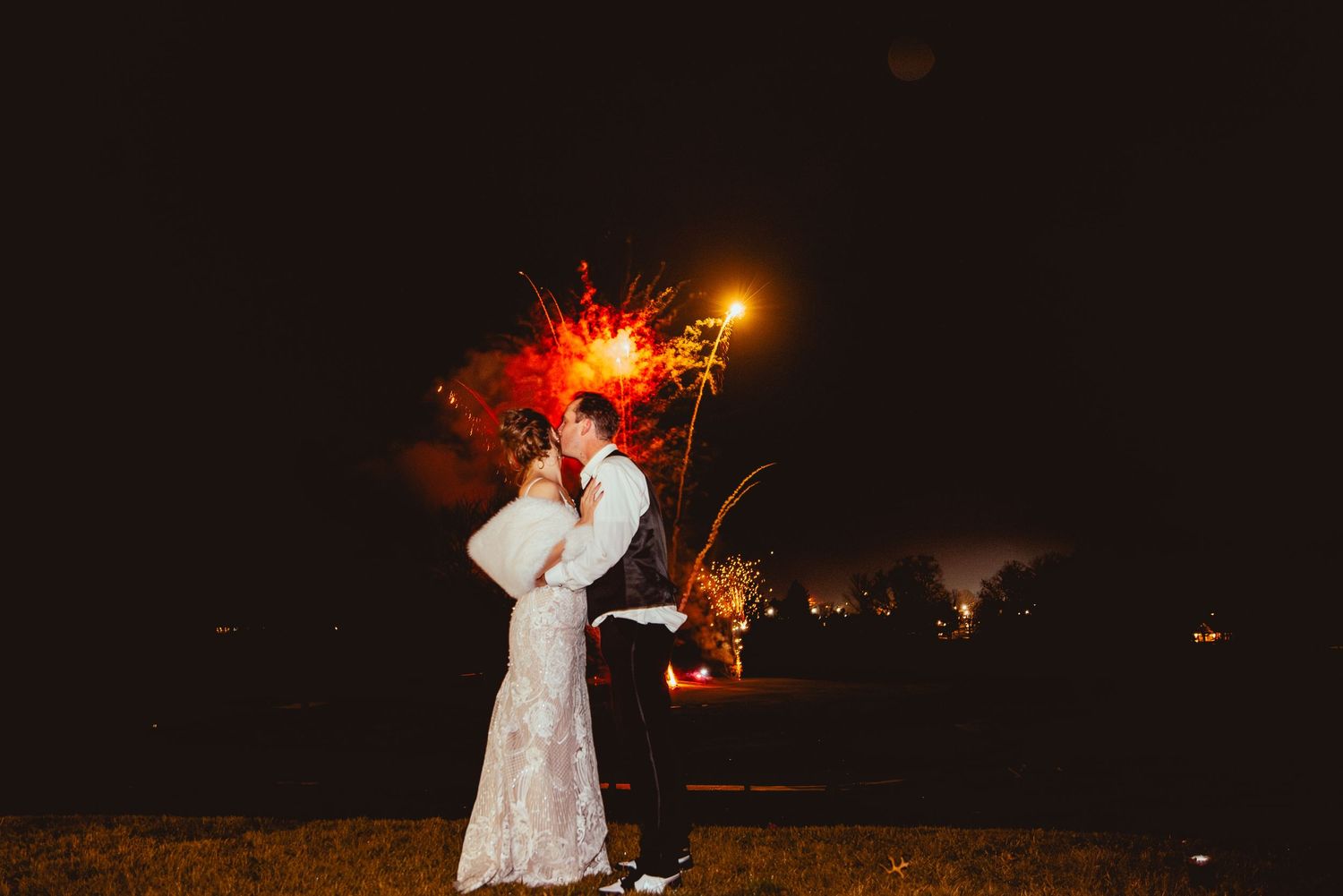 Natural, documentary-style wedding photo – groom kisses bride during Danville fireworks