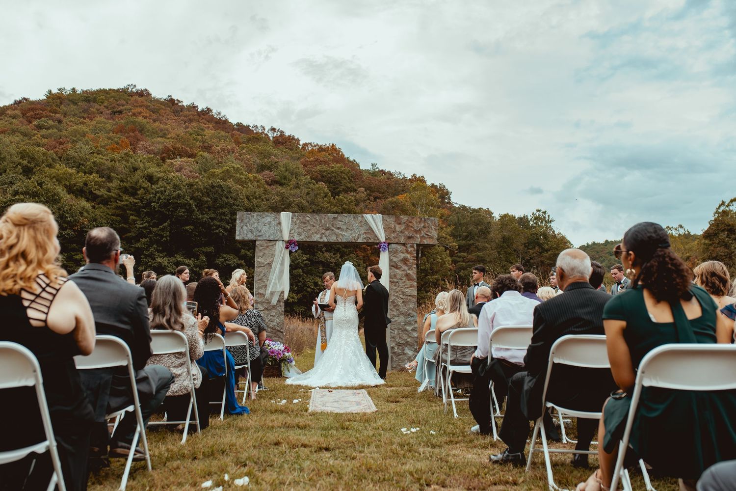 White chairs set up for an outdoor wedding ceremony with rolling hills in the background.