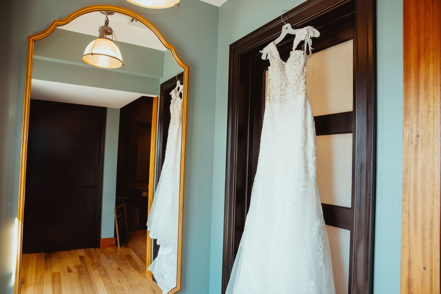 Wedding dresses displayed on hangers in a bridal boutique with warm lighting and wooden accents.