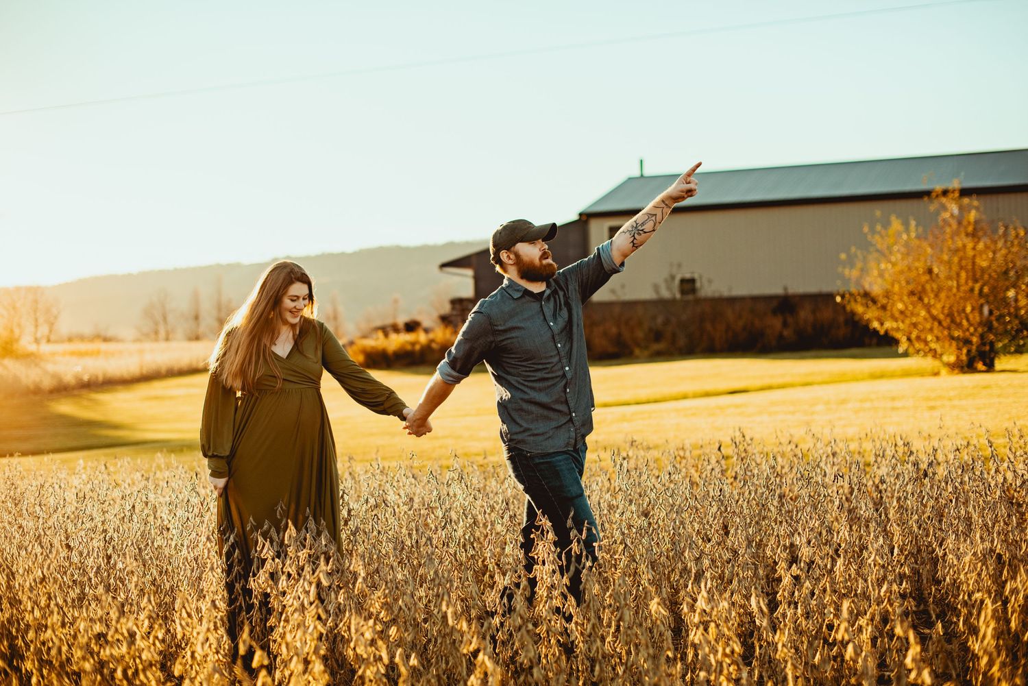 Two people holding hands and running through a golden wheat field at sunset with warm lighting.