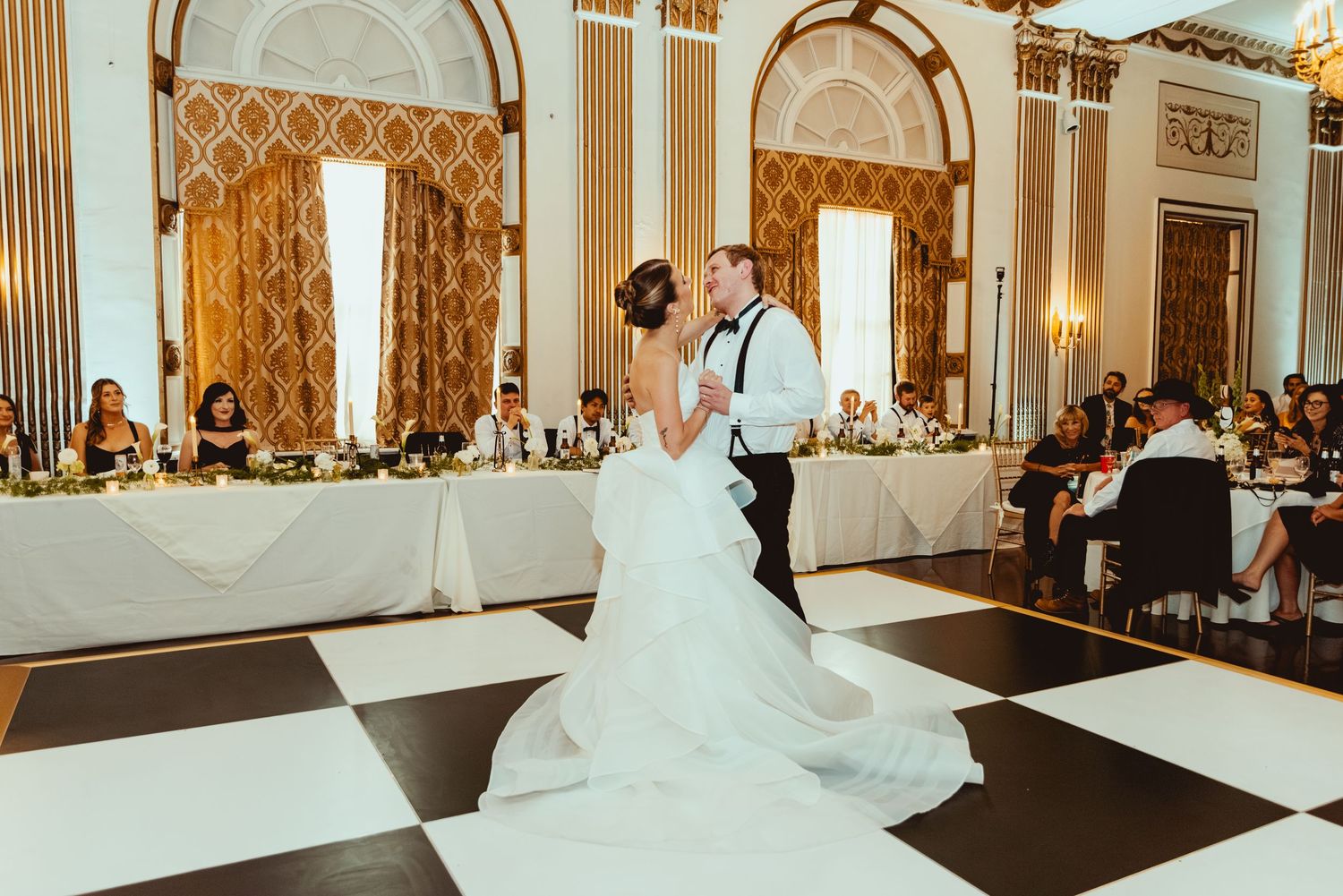 A ballroom wedding reception setup with elegant tables, chairs, and chandeliers in a grand venue.