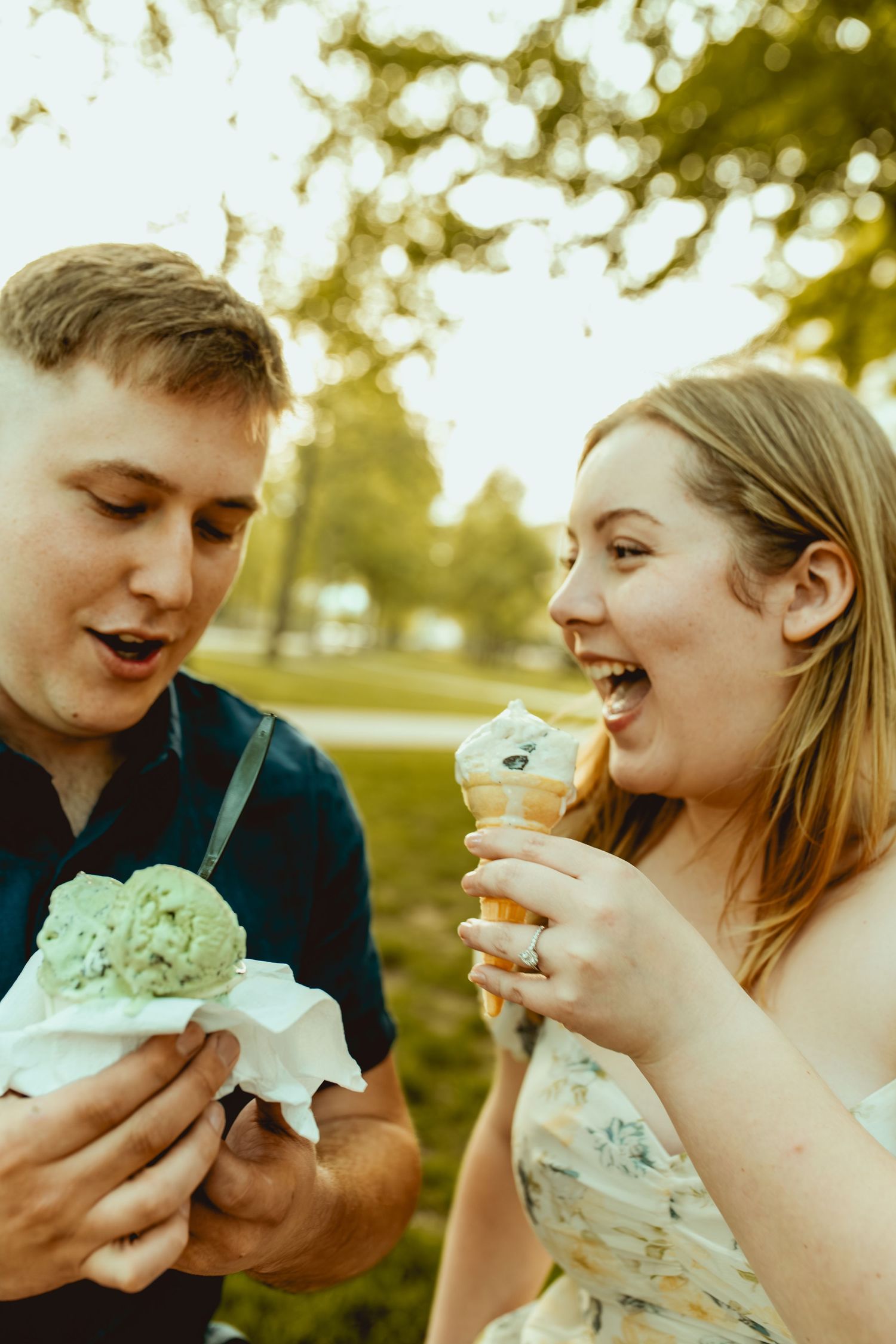 A happy couple enjoying ice cream cones together outdoors in a sunny park setting.