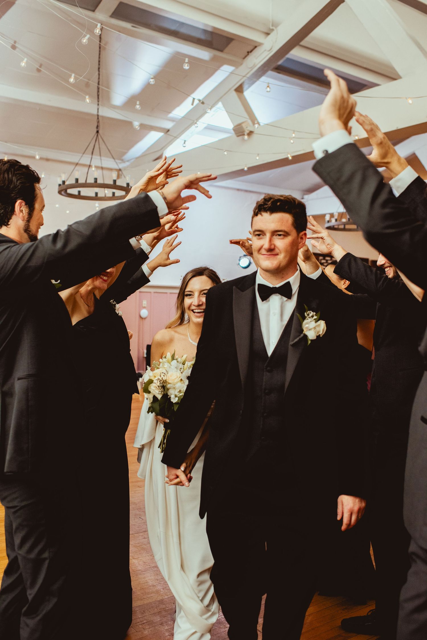 Wedding party dancing and celebrating with raised arms on a dance floor at a reception.