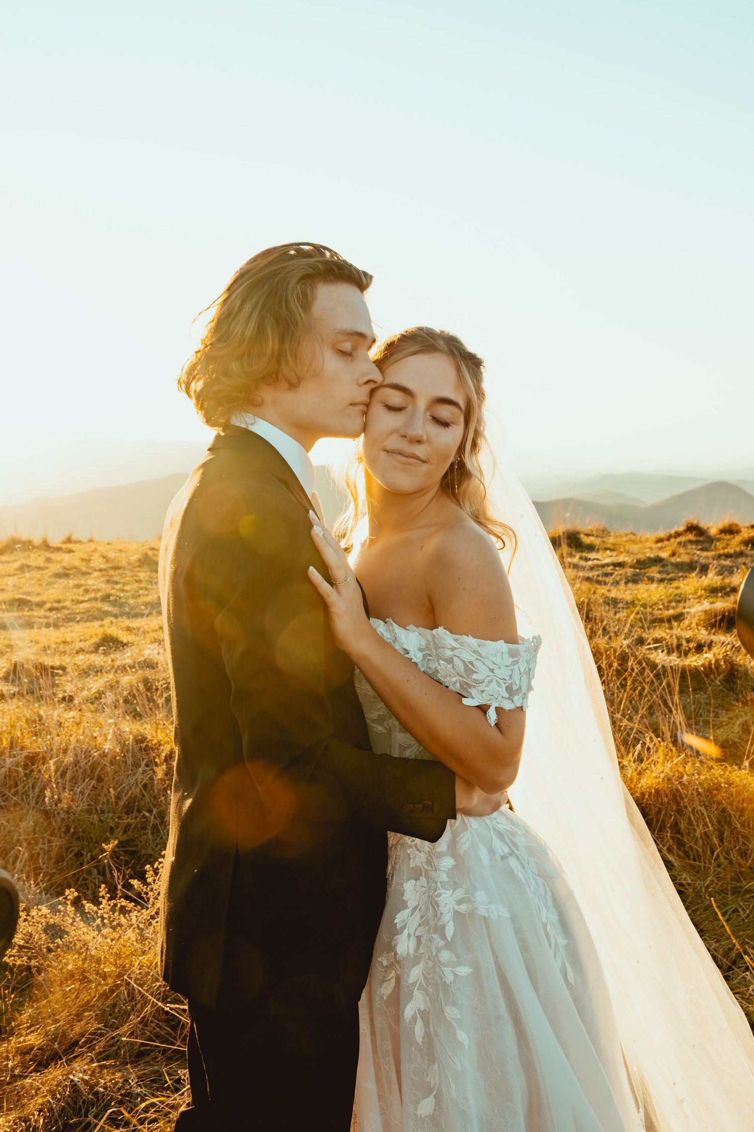 Intimate wedding couple embracing during golden hour in a mountain setting.