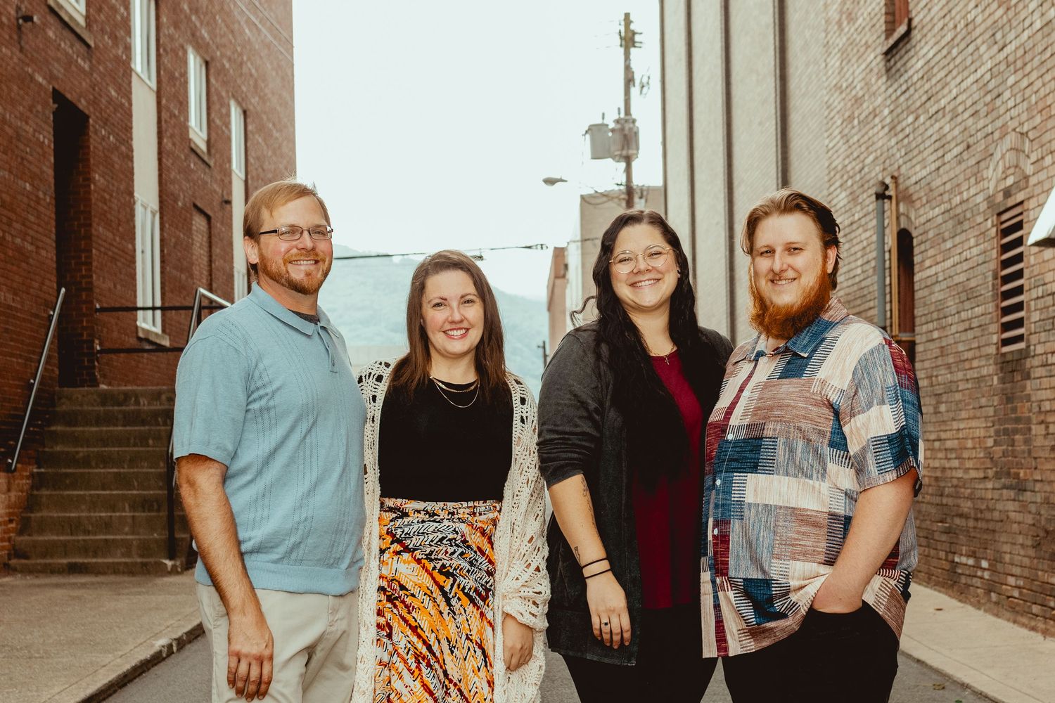 Casual group photo in an urban setting with brick architecture and metal details visible.