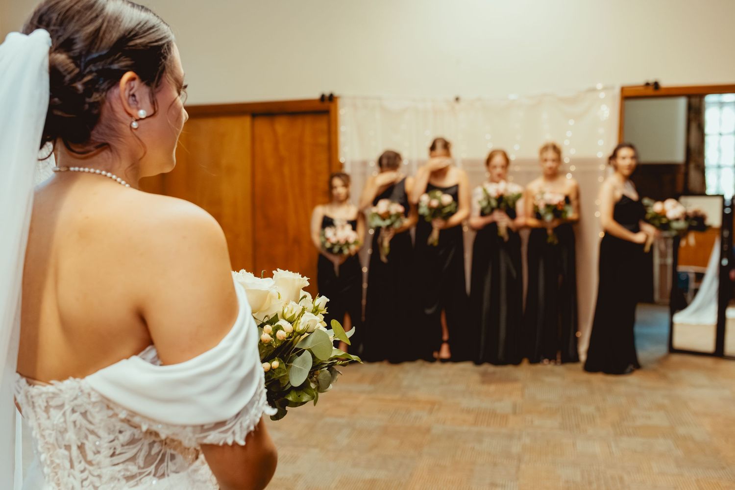 A bride and groom share their first dance at a wedding reception while guests watch from tables in the background.