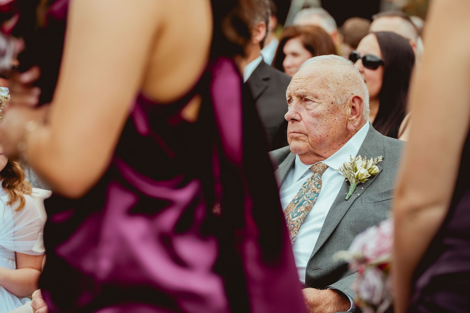 Wedding ceremony guests seated in rows wearing formal attire.