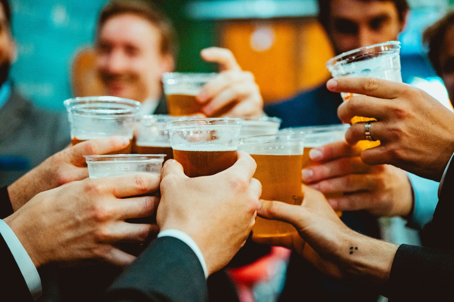 Multiple hands holding drinks together in a celebratory toast moment.