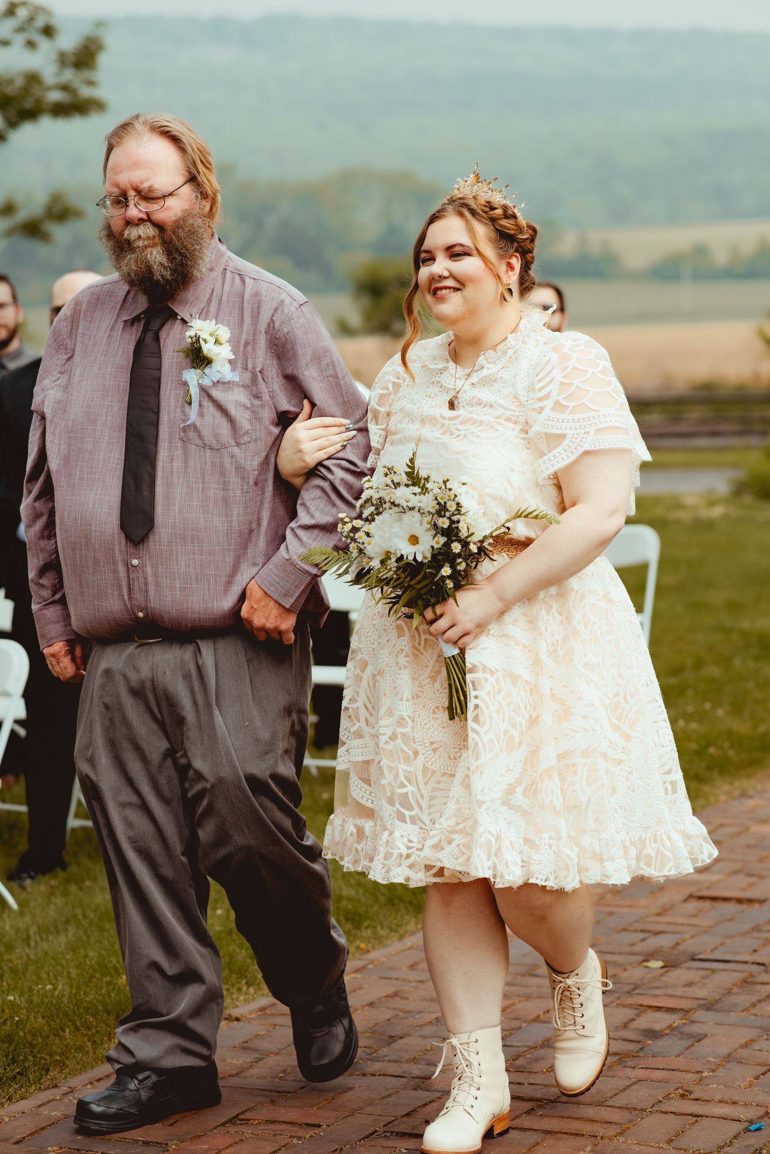 A couple in wedding attire share a playful moment on a brick patio with mountains in the background.