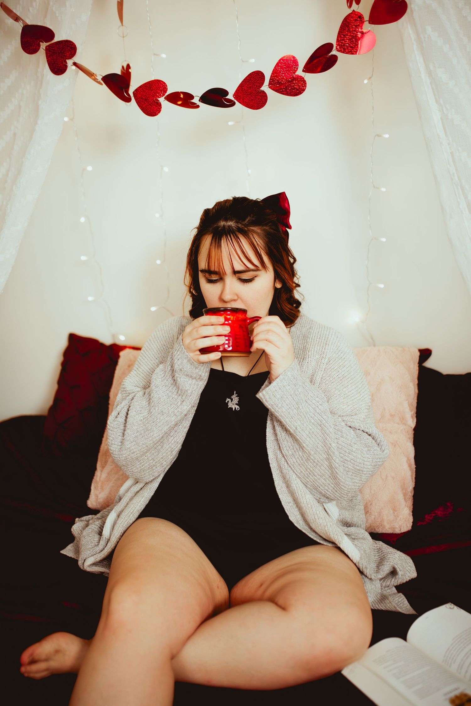 Red heart garland decorates white fabric backdrop with moody lighting and romantic Valentine's Day aesthetic.