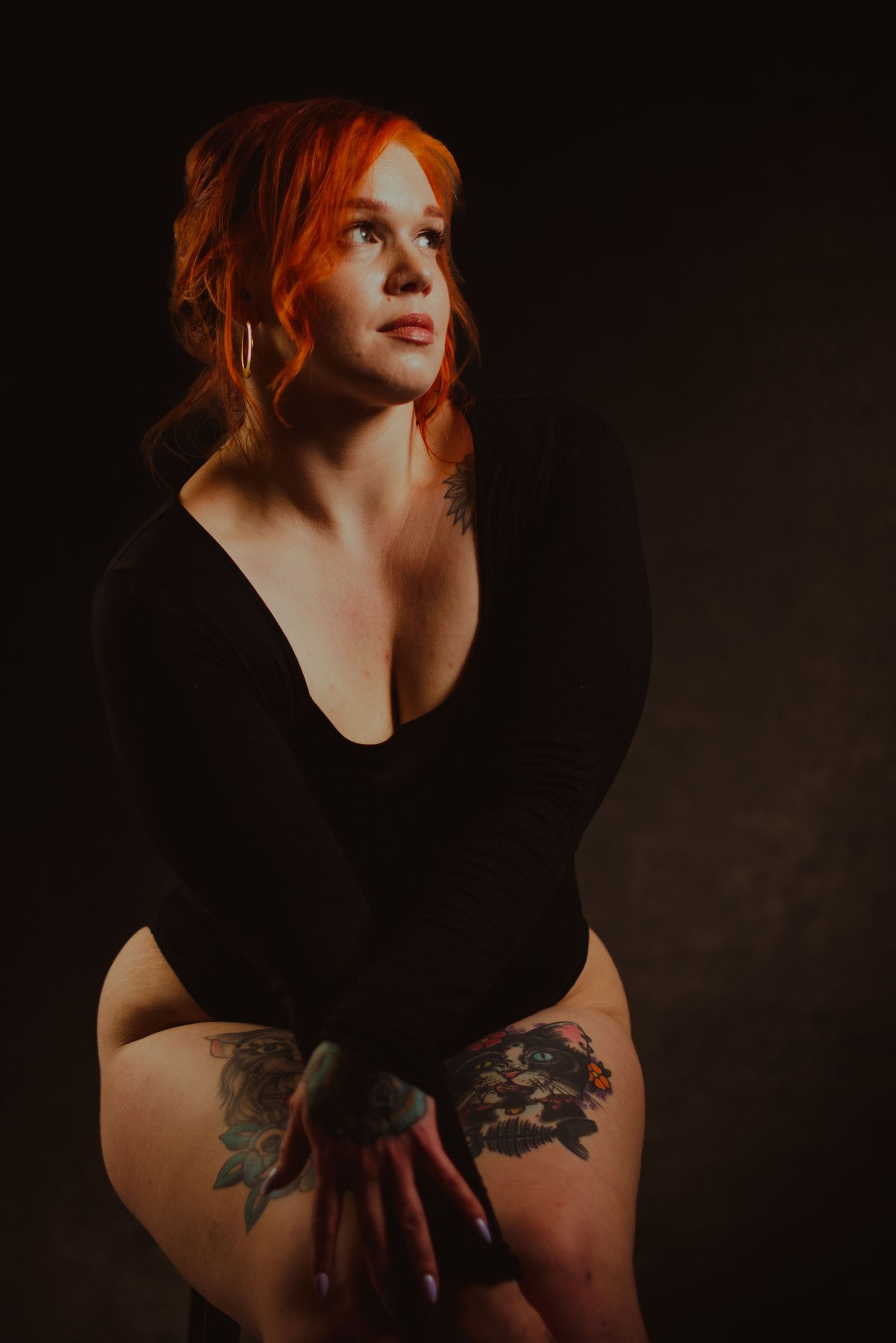 Dramatic low-key photography featuring dark aesthetics and artistic tattoo details in black attire.