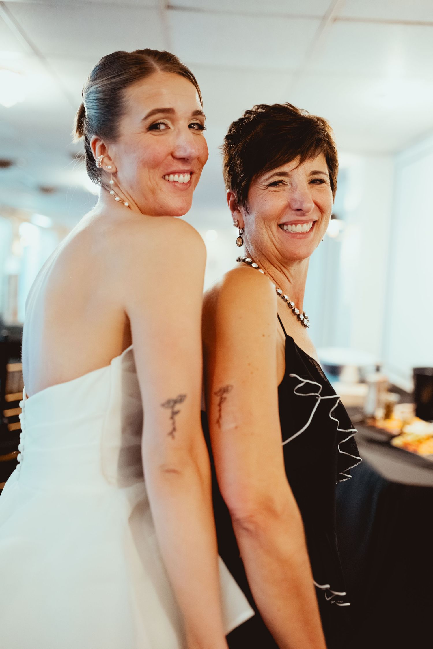 Two people in formal attire share a joyful moment at an indoor wedding celebration.