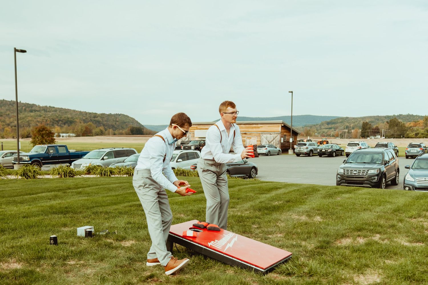 Guests enjoying outdoor lawn games and cornhole at a sunny wedding reception venue.
