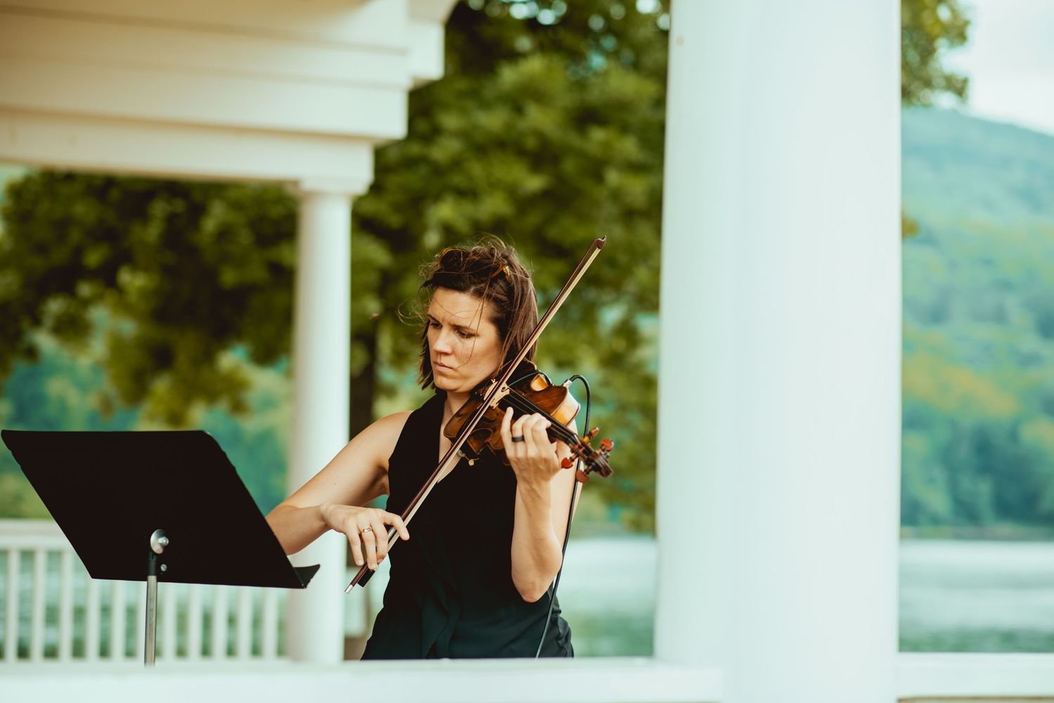 Musicians performing on an elegant white columned porch with scenic mountain views.