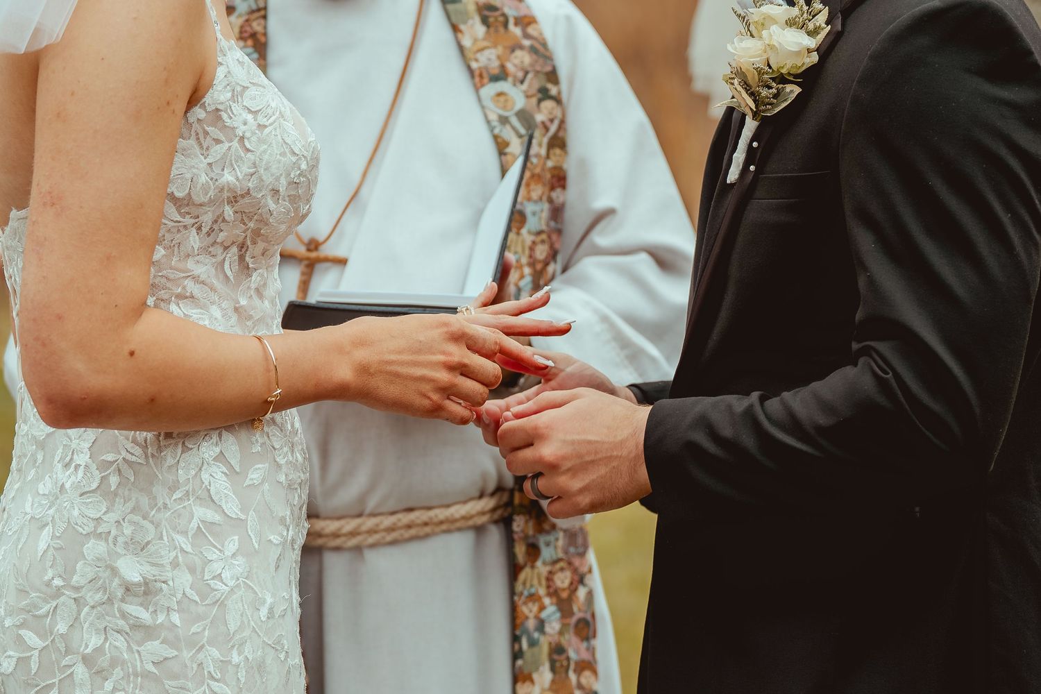 Close up of wedding ceremony showing hands exchanging rings during vows.