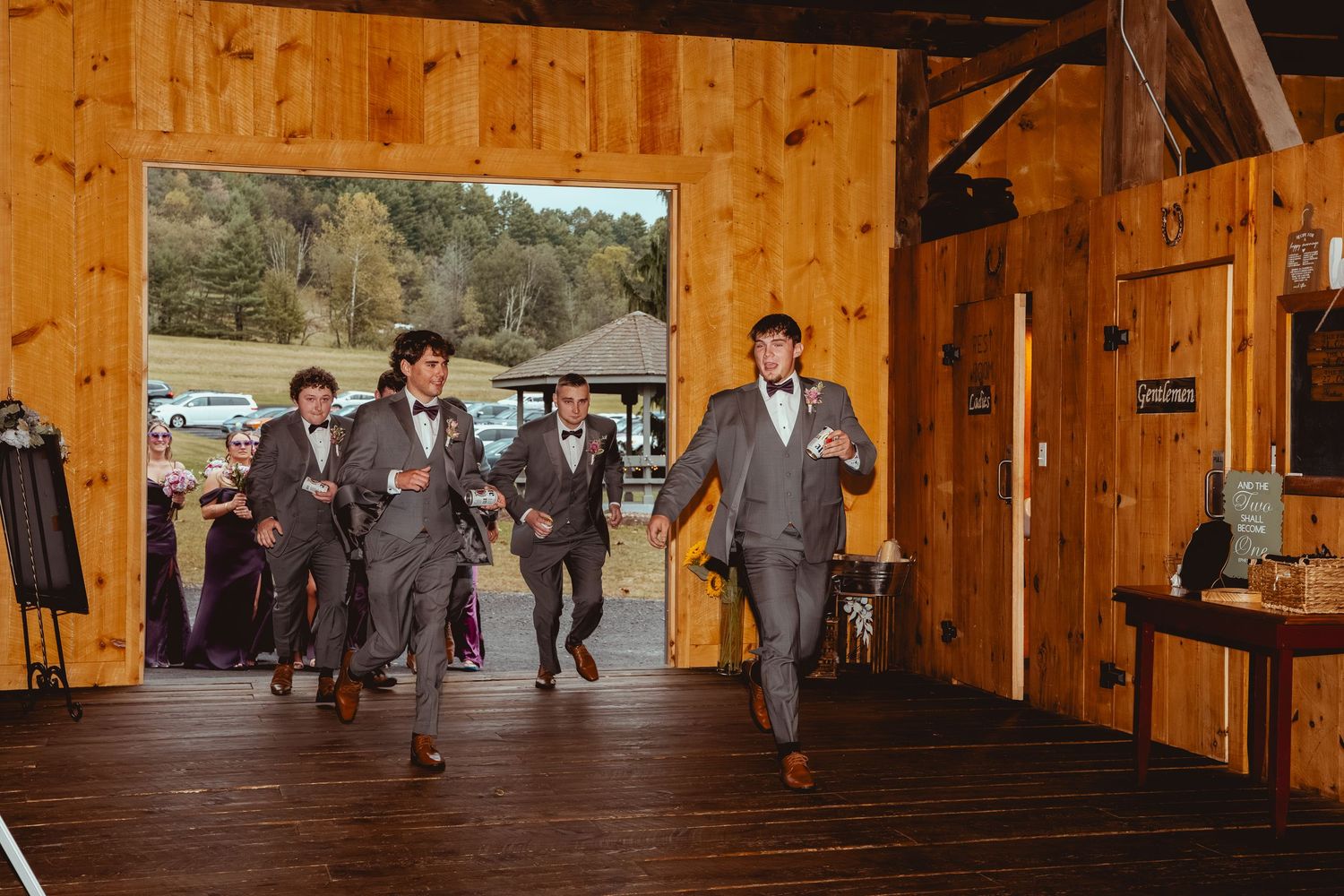 Wedding reception in rustic wooden barn venue with exposed beams and warm lighting.