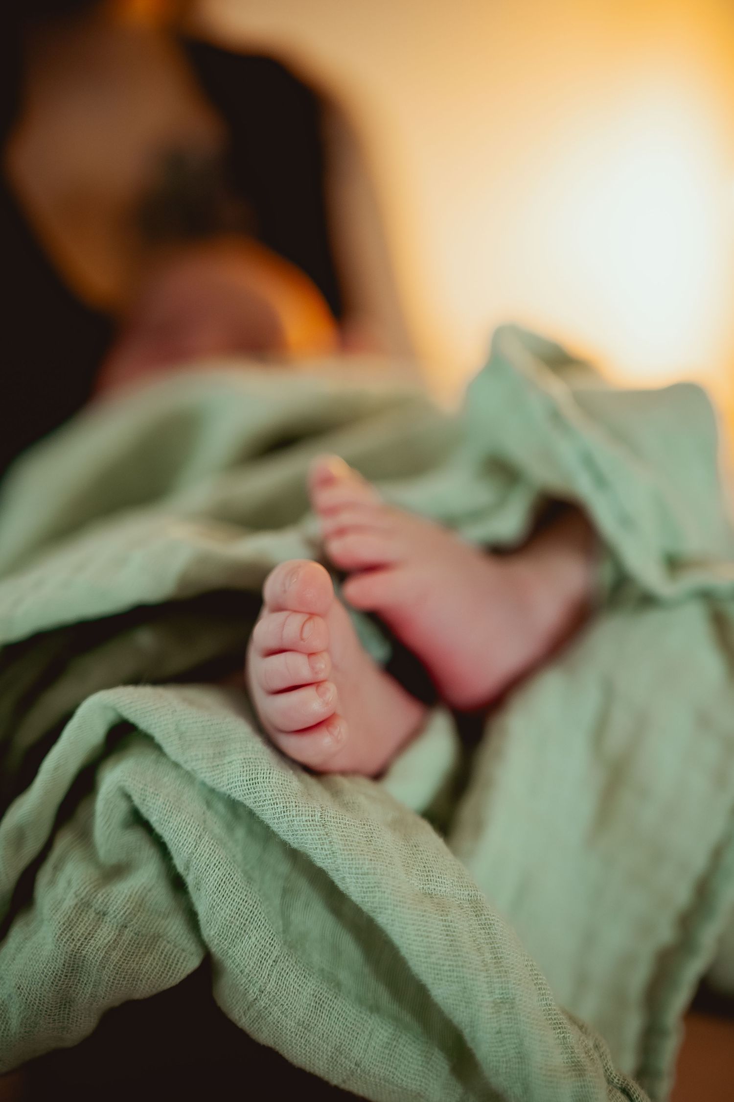 A series of close-up photos showing tiny baby feet wrapped in soft mint green fabric in warm lighting.