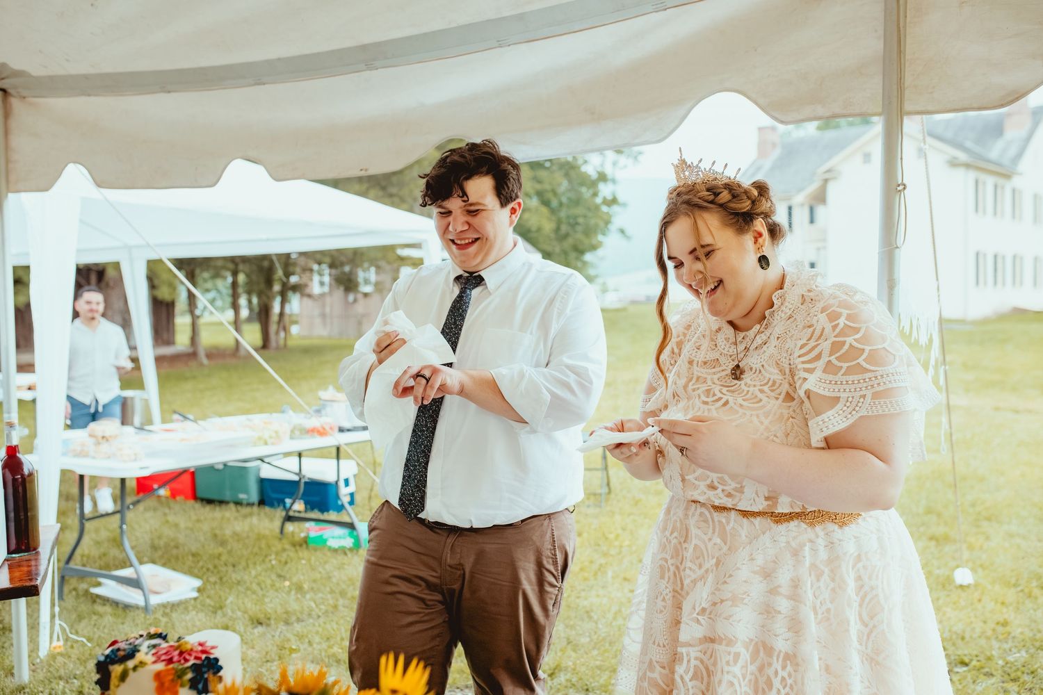 A group of people in vintage period costumes gather outdoors under white tents at a historical reenactment event.
