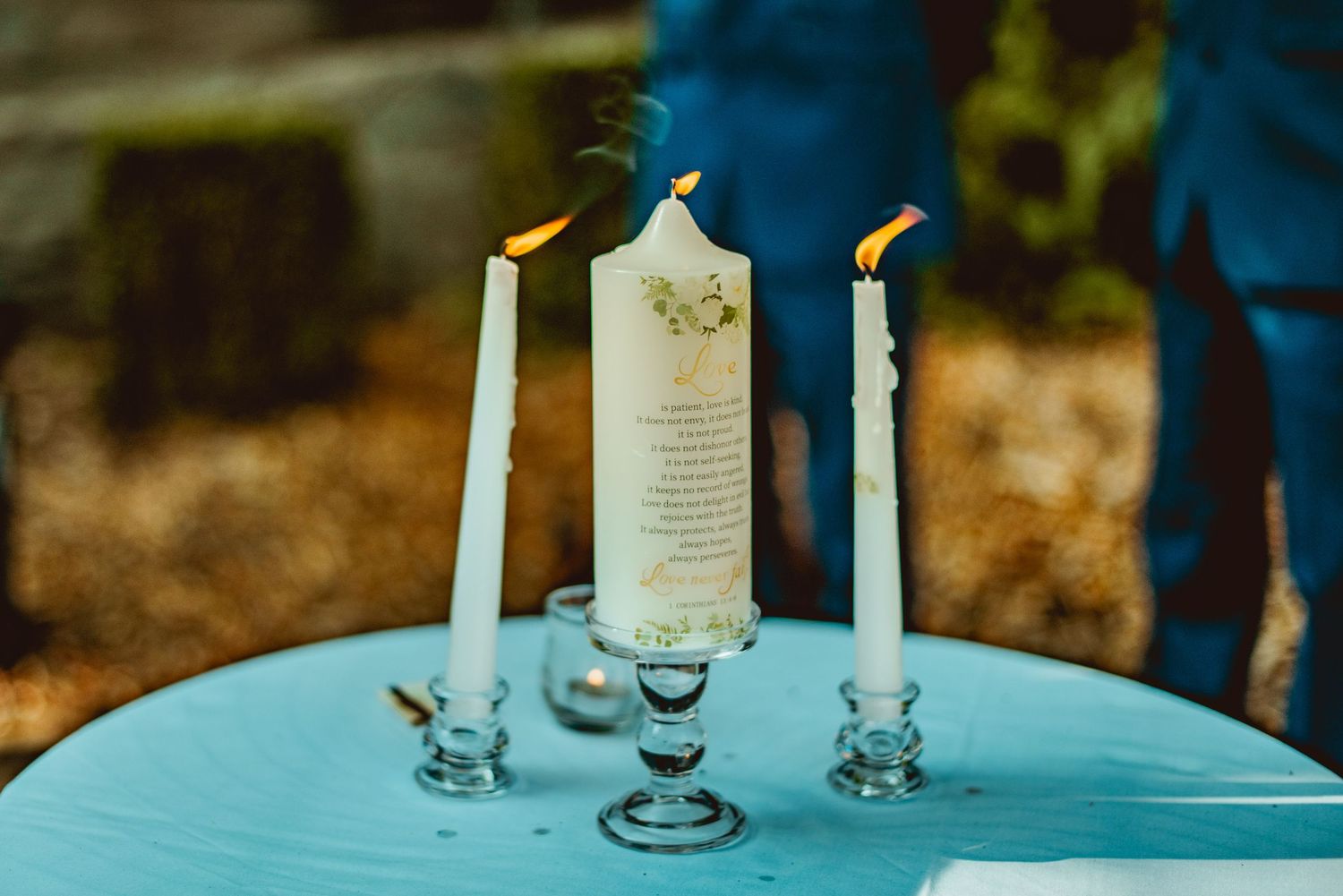 White candles arranged on a wooden table create an elegant rustic wedding reception setting.
