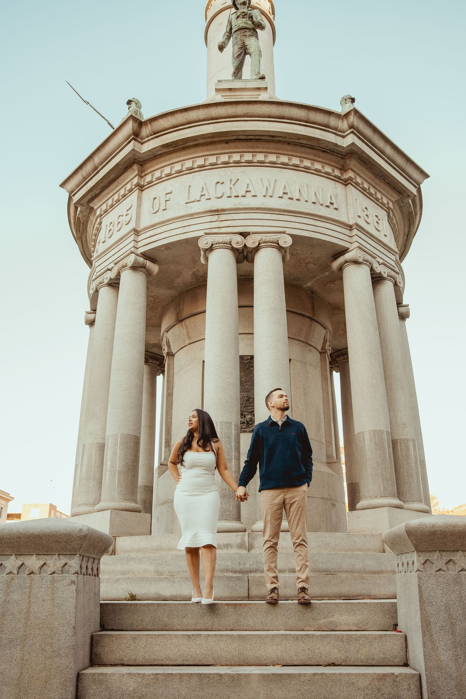 A couple poses on the steps of a neoclassical building with white columns and 'Lackawanna' signage.