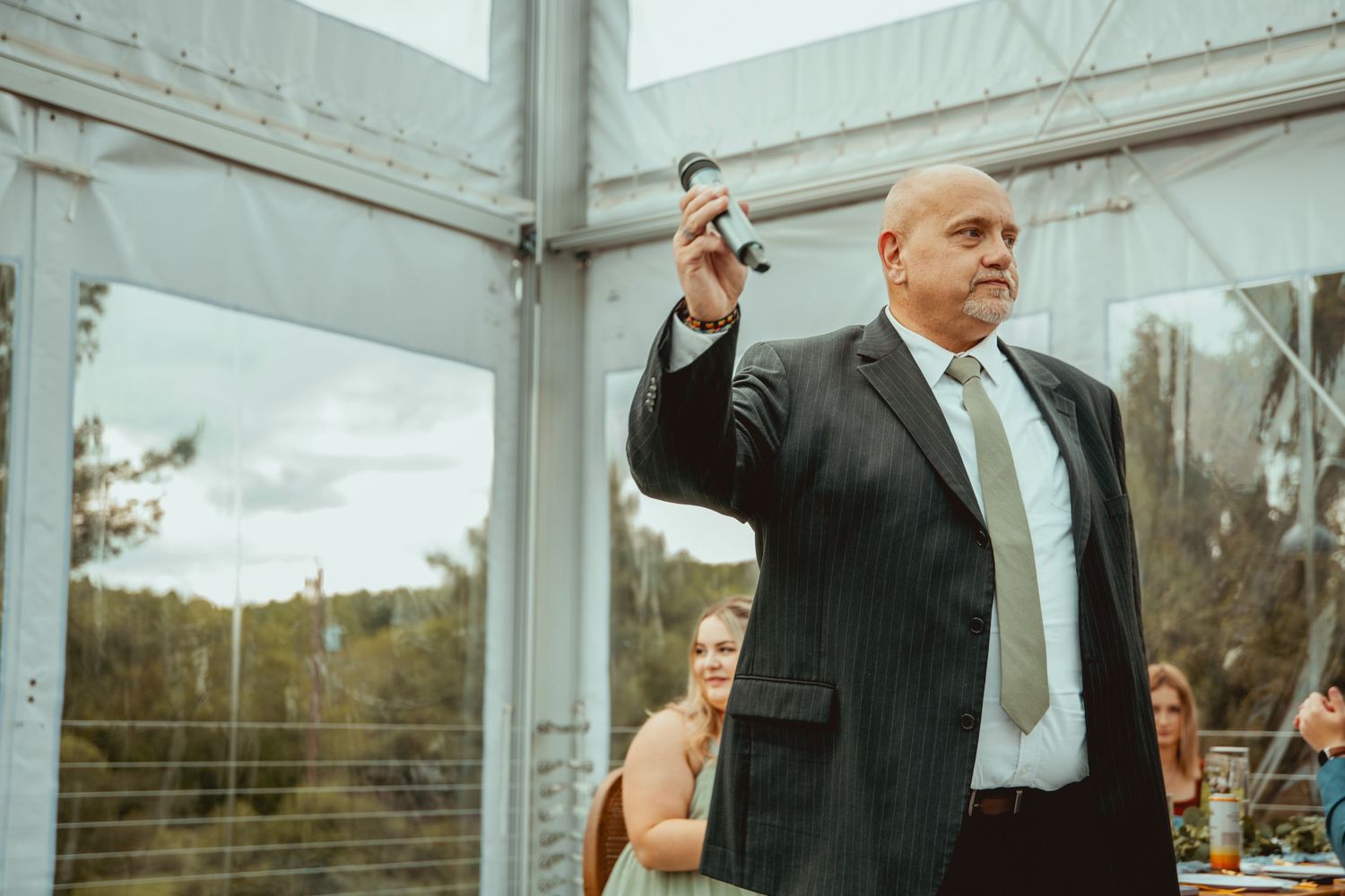 Wedding celebration in a white tent with guests mingling in formal attire.