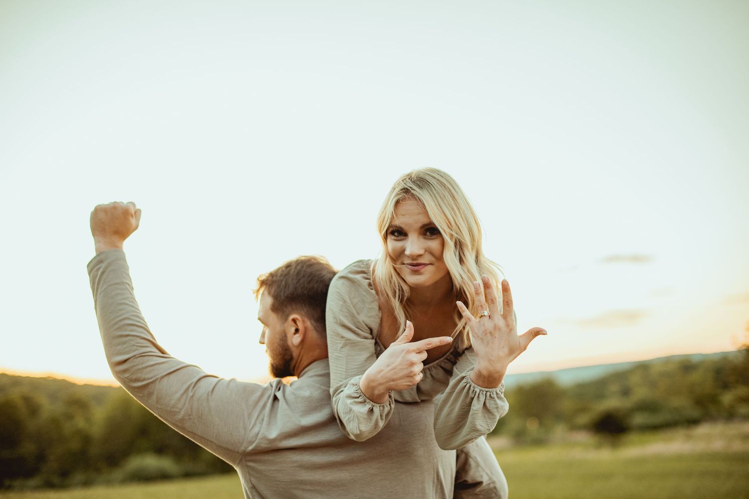 A couple dancing and twirling together in a field during golden hour.