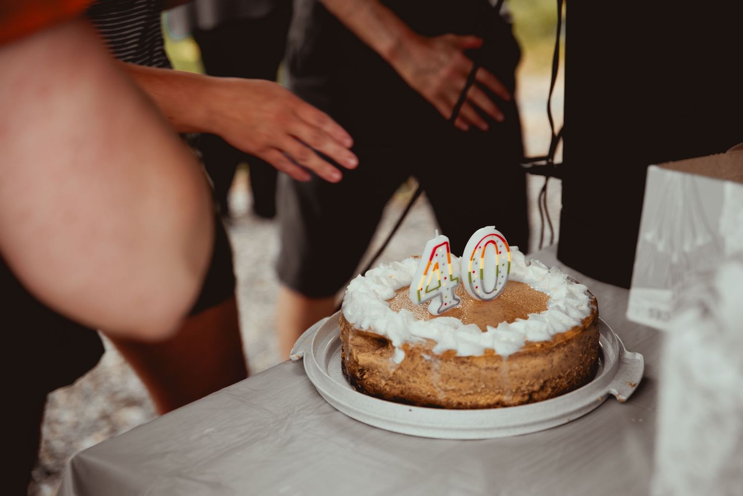 Multiple slices of a cream-topped cake being served and shared at a gathering.